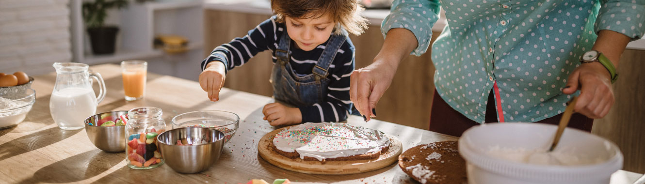 A mom and her young child baking in a large kitchen.