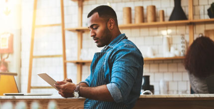 Business owner inside his shop looking down at a tablet.