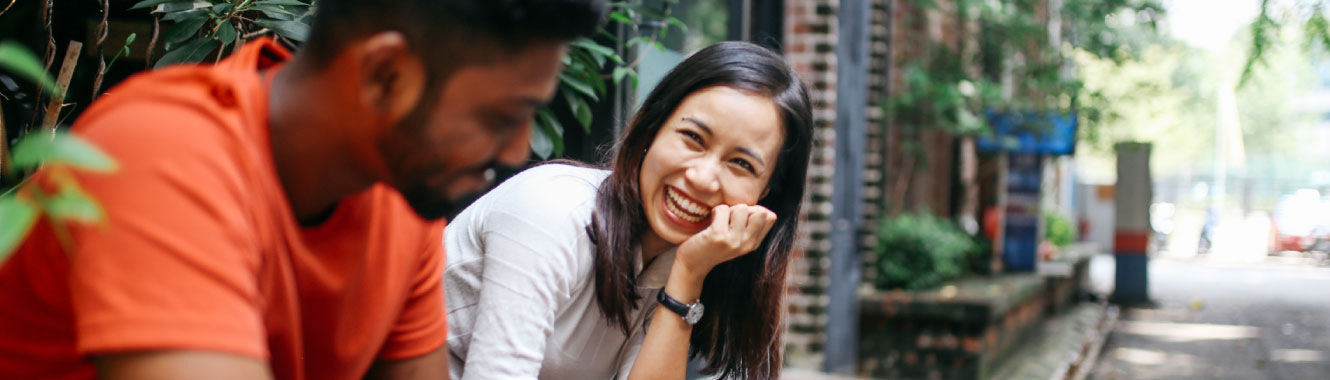 Two friends sitting outside and laughing. 