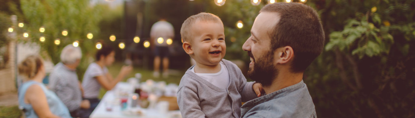 A dad holding his son outside, they are both laughing.
