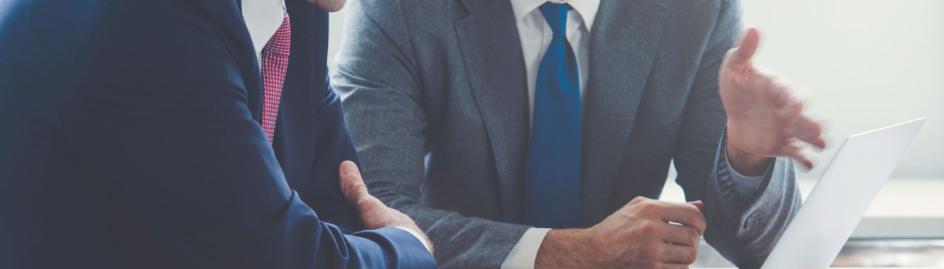 Close up of two businessmen's hands motioning towards a laptop screen.