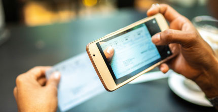 Close up of a person's hands taking a picture of a check with a smartphone.